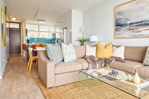 A modern living room with a sofa, coffee table, and a chess set. - Two Bed Green Point Ocean View (Cape Town)