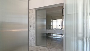 A modern bathroom with a glass shower enclosure, marble flooring, and a visible sink area. - Elegant One Bed Sea Point Mountain Views (Cape Town)