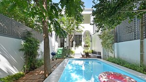 A rectangular pool with a floating ring, surrounded by a brick pathway and greenery. - Elegant Three Bedroom Home (Cape Town)