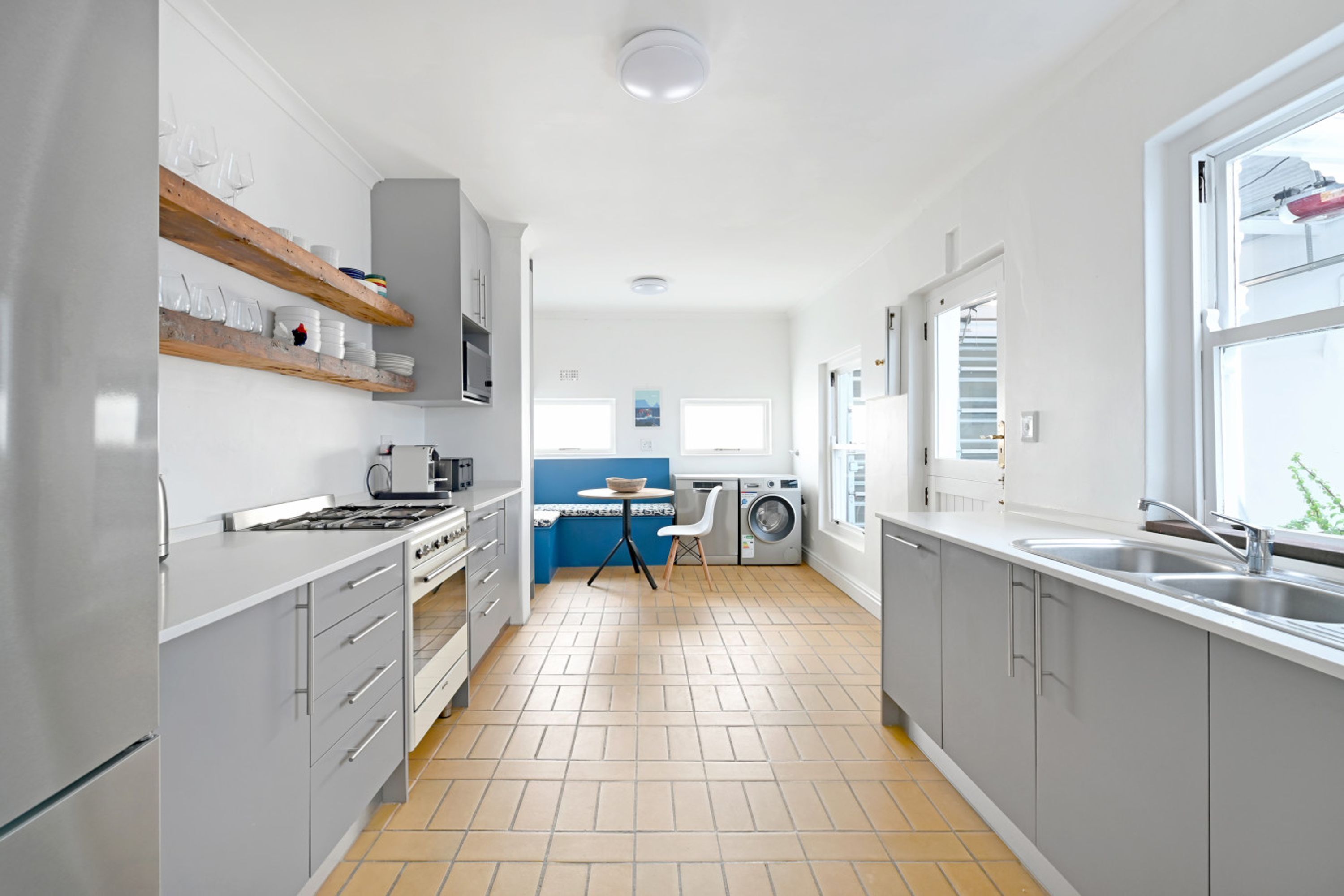 Una cucina moderna con mobili grigi, forno integrato e lavatrice.