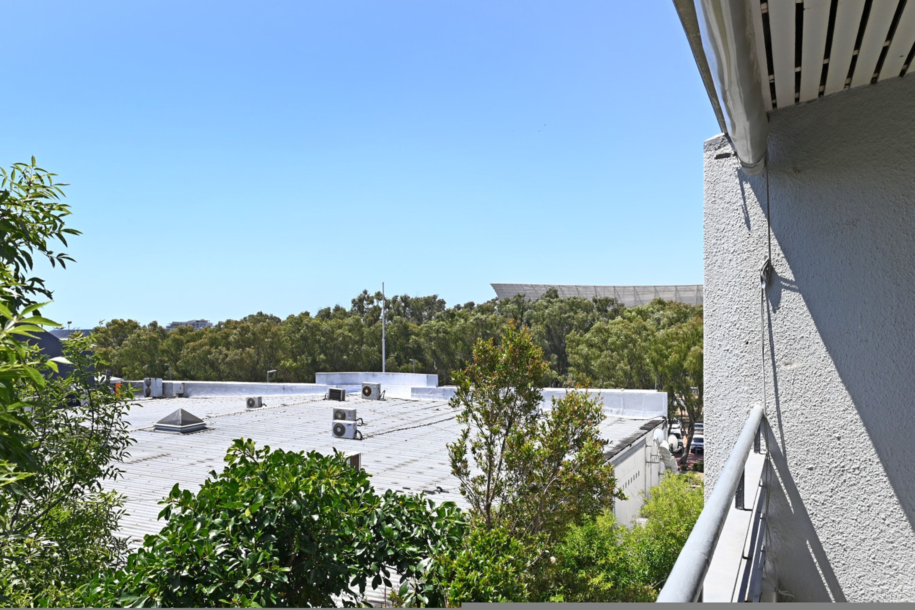 Et tag med flere ventilationsanlæg, omgivet af grønt og en klar himmel.
