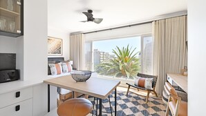 A modern kitchen with a dining area, large windows, and a view of palm trees. - Green Point Micro Lock Up and Go (Cape Town)