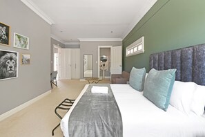 Ein modernes Schlafzimmer mit einem großen Bett, einer grauen Kopfstütze und Blick ins Wohnzimmer.