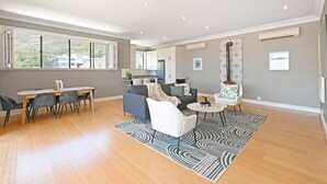 A spacious living area with a dining table, sofas, and a kitchen in the background. - Two Bed Table Mountain Spacious (Cape Town)