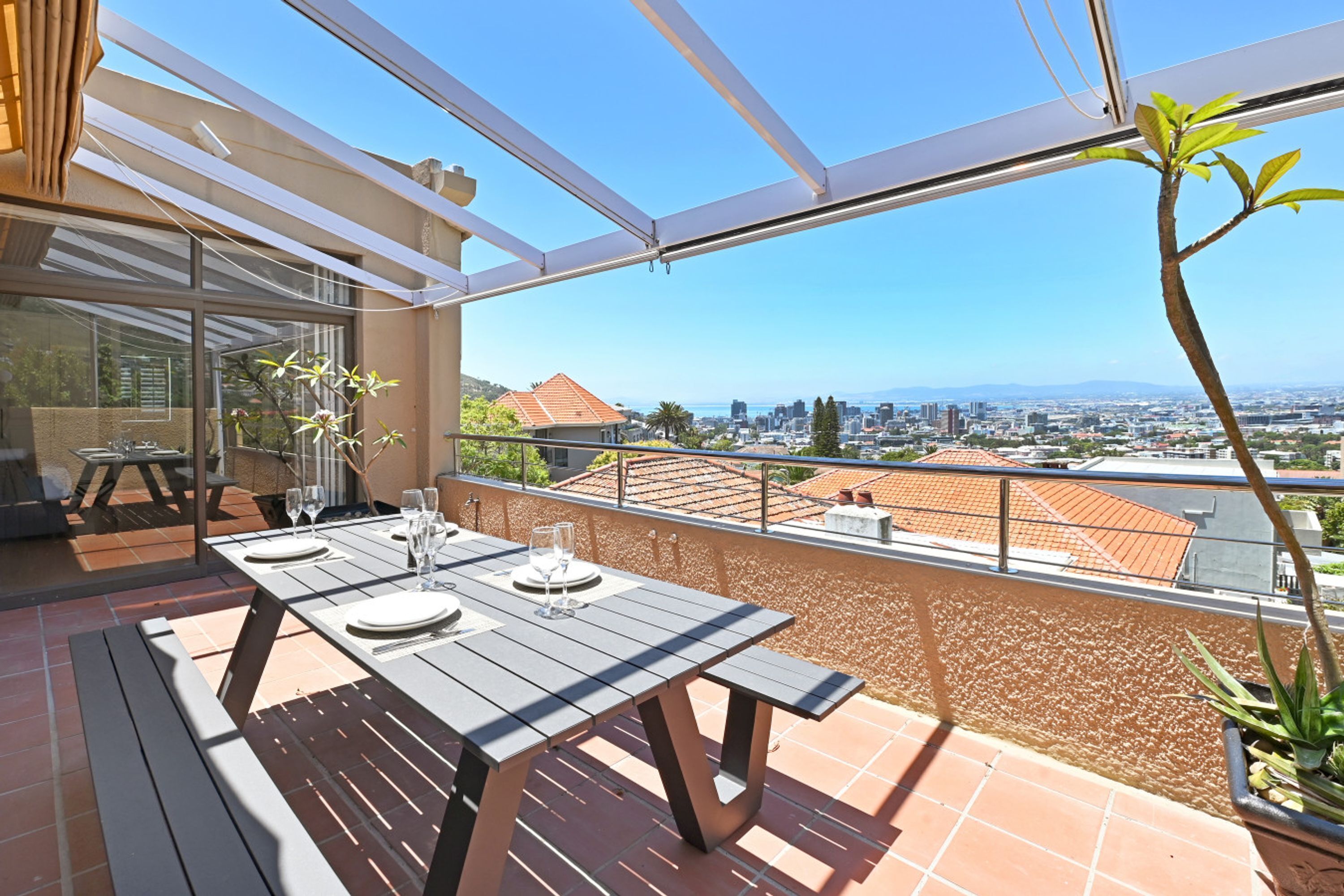 A balcony with a table set for dining, overlooking a cityscape.