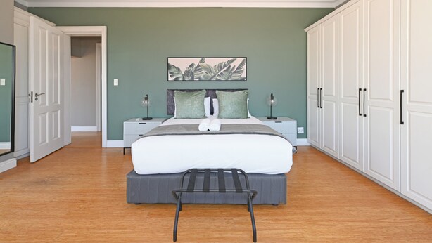 Une chambre à coucher avec un lit, des tables de chevet, un banc, une armoire et un tableau au mur.