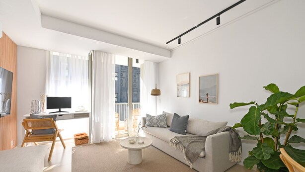 En moderne stue med en sofa, et sofabord og en stor plante.
