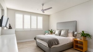 Un dormitorio moderno con cama, mesita de noche y ventilador de techo.