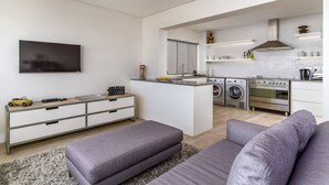 Una cocina moderna con una isla central, electrodomésticos integrados y un televisor de pantalla plana.
