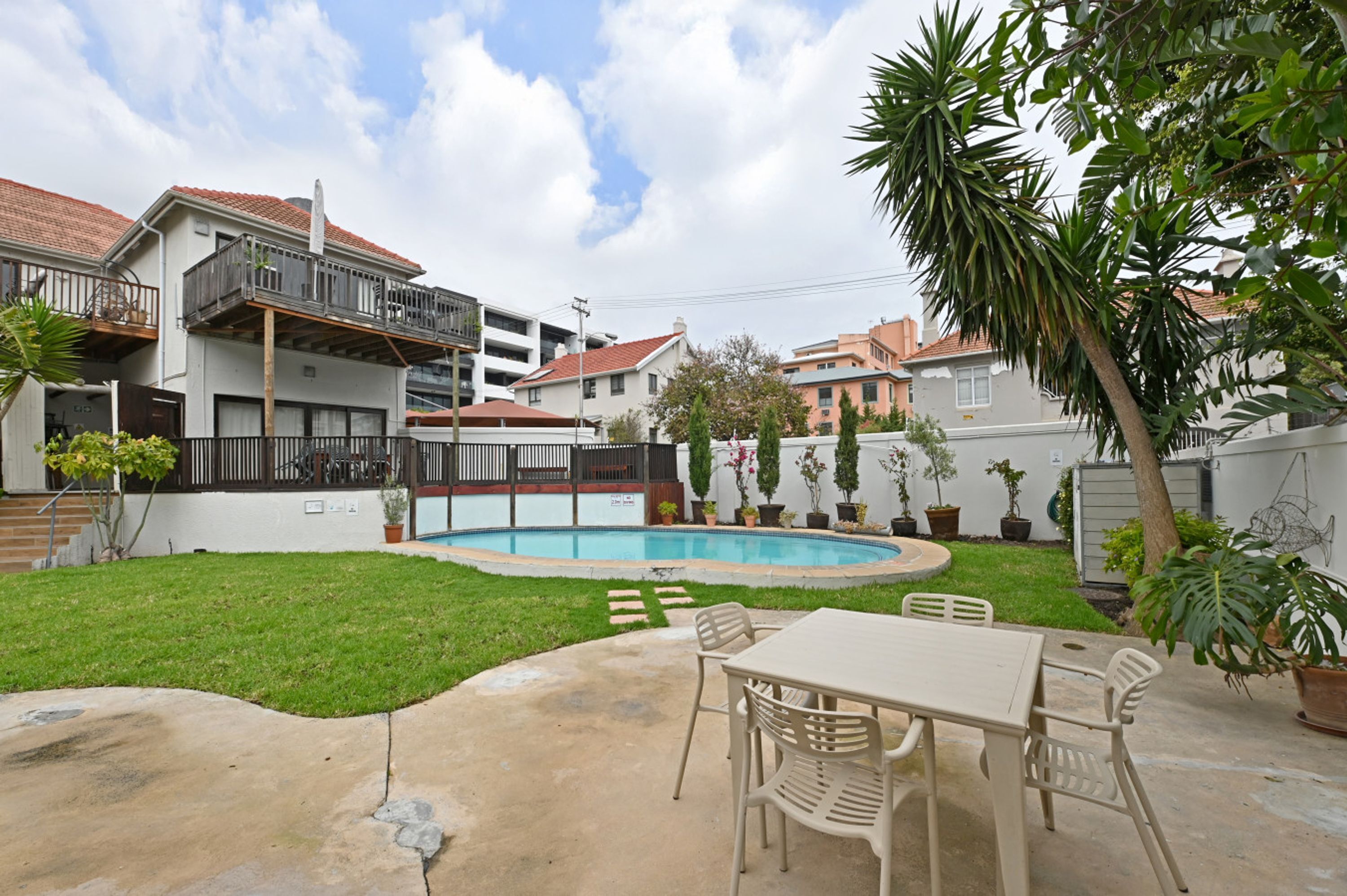 Ein Garten mit Pool, Terrassentisch und Stühlen.
