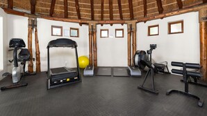 Een sportschool met trainingsapparatuur, een yogamat en een gele fitnessbal.