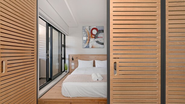 Una camera da letto moderna con una testiera in legno, una grande finestra e un quadro appeso al muro.