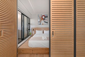 Ein modernes Schlafzimmer mit einem Holz-Kopfteil, einem großen Fenster und einem Gemälde an der Wand.