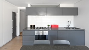 Una cucina moderna con mobili grigi, un lavello in acciaio inossidabile e un tostapane rosso.