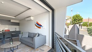 Un appartamento moderno con un divano grigio, un tavolino rotondo e un angolo cottura.