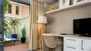 A modern room with a desk, chair, lamp, TV, and potted plants. - Sea Point Oasis Private Garden Pool Gym and BBQ (Cape Town)