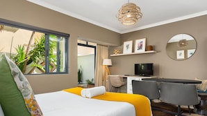 A hotel room with a bed, a desk, a chair, a television, and a view of the outdoors. - Sea Point Oasis Private Garden Pool Gym and BBQ (Cape Town)