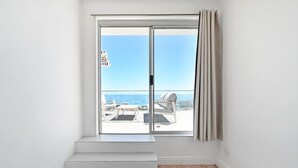A room with a view of the sea through a sliding glass door, a wooden floor, and a white wall. - Spacious 3 Bedroom Villa BBQ Pool Ocean View (Cape Town)