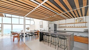 A modern kitchen with a large island, bar stools, and a view of the sea. - Spacious 3 Bedroom Villa BBQ Pool Ocean View (Cape Town)