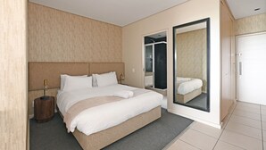 Moderni hotellihuone, jossa on suuri sänky, vaatekaappi ja peili.