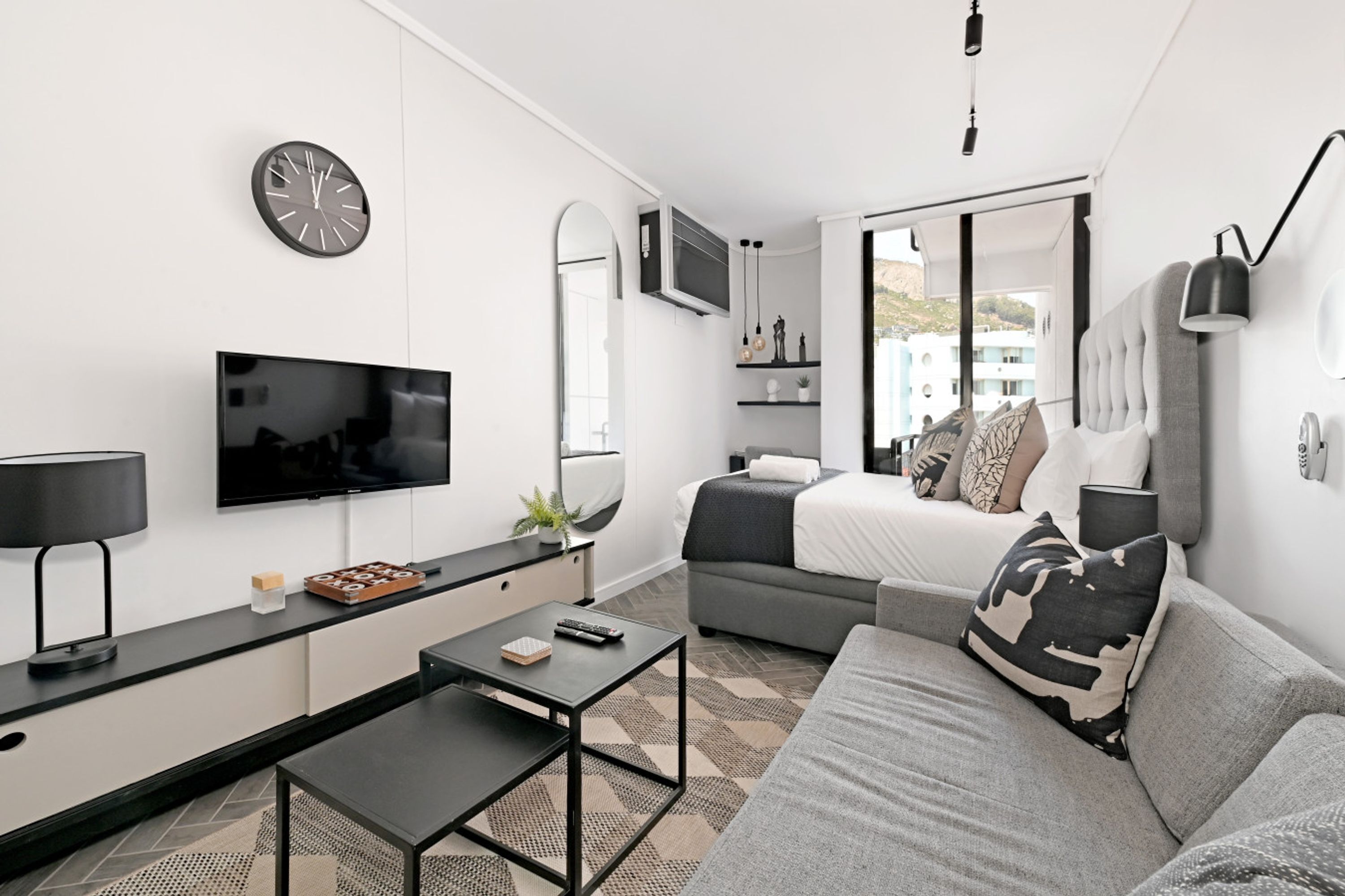 A modern, well-lit living room with a flat-screen TV, a sofa, a coffee table, and a dining table.