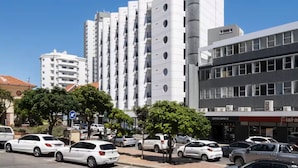Un edificio moderno de varios pisos, con una cafetería en la planta baja y automóviles estacionados al frente.