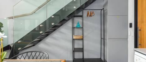A modern kitchen with a grey refrigerator, a built-in oven, and a glass staircase.