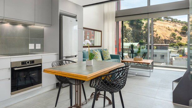Une cuisine moderne avec un coin repas, de grandes fenêtres et une vue sur une colline.