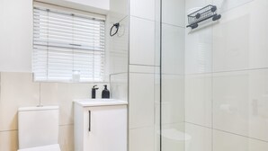 Une salle de bain moderne équipée de toilettes, d’un lavabo et d’une douche à parois de verre.