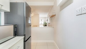 Une cuisine moderne dotée d’un réfrigérateur en acier inoxydable, de meubles blancs et d’un design épuré et minimaliste.
