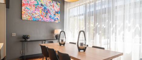 A modern dining area with a wooden table, black chairs, and pendant lighting.