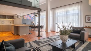 A modern living room with a sofa, coffee table, and a dining area with chairs and a table. - Two Bed Designer Luxury Central De Waterkant (Cape Town)