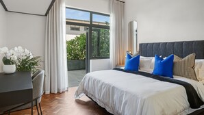 A modern bedroom with a large bed, a desk, and a potted plant. - Two Bed Designer Luxury Central De Waterkant (Cape Town)