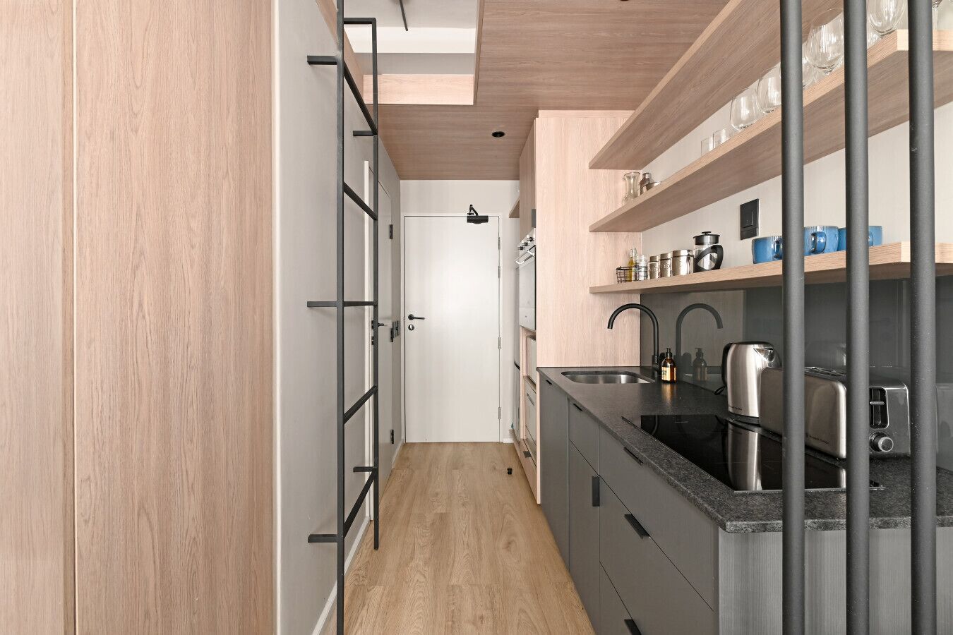 A modern kitchen with a black countertop, stainless steel appliances, and wooden cabinetry.