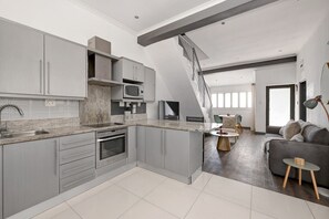 Une cuisine moderne avec des meubles gris, un four à micro-ondes encastré et un grand îlot central.