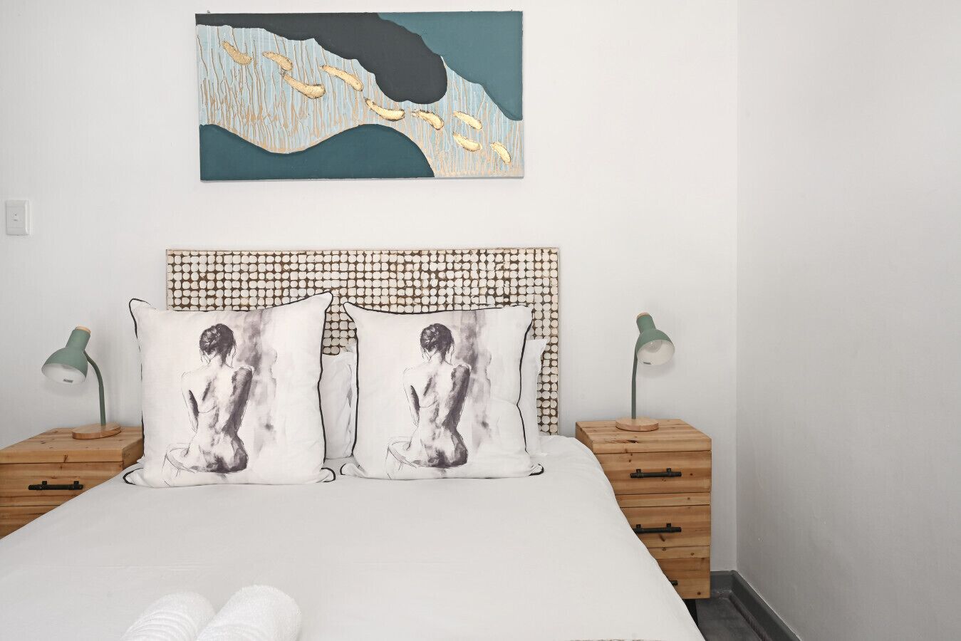 Ein Schlafzimmer mit einem Bett, zwei Nachttischen, einem Kopfteil und einem Wandbild.