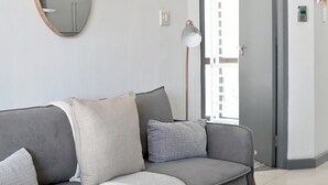 Moderni olohuone, jossa on harmaa sohva, pyöreä peili ja lattiavalaisin.