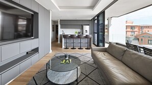 Egy modern apartman, amely amerikai konyhával, étkezővel és egy kanapéval és asztallal berendezett erkéllyel rendelkezik.