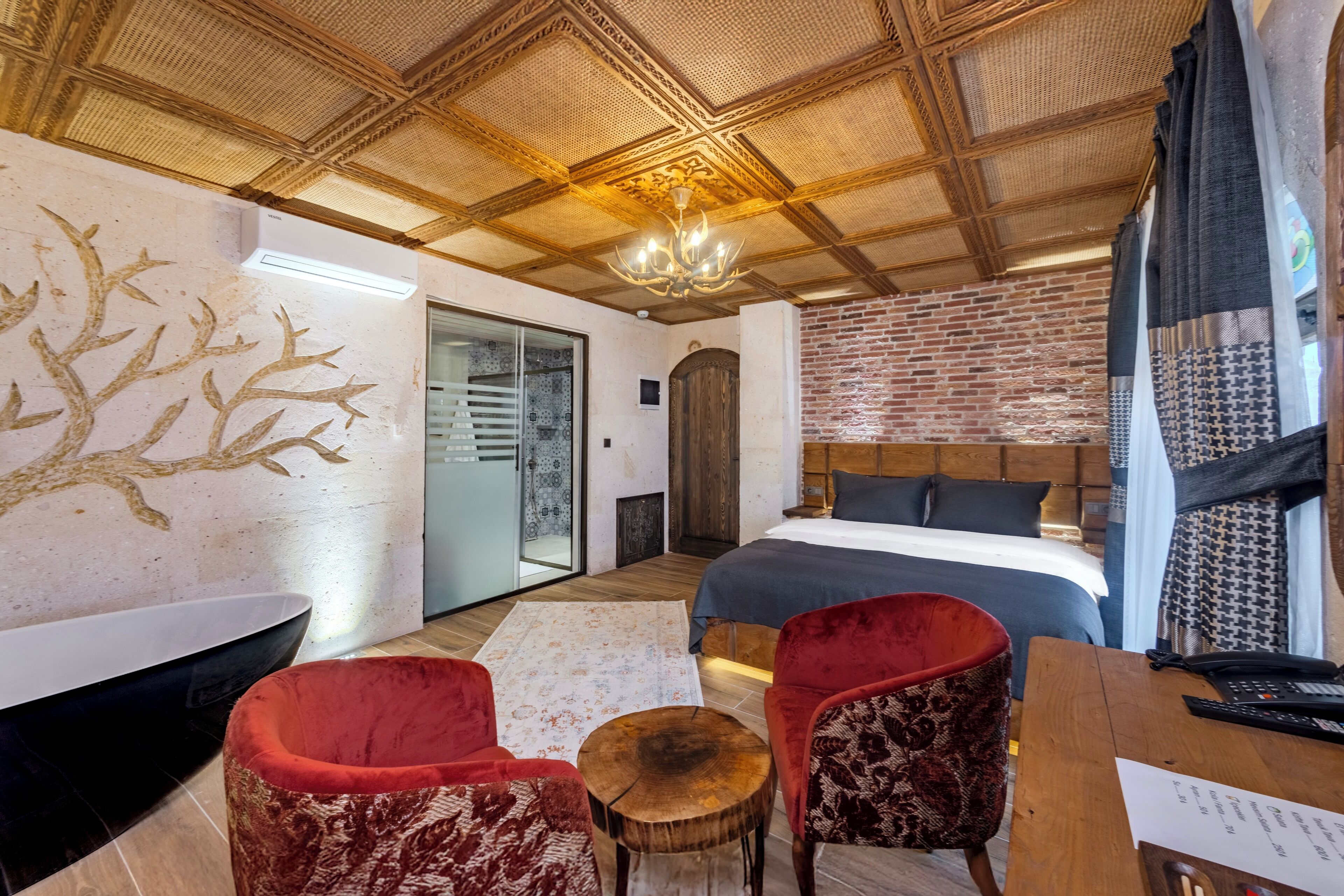 Ein modernes Schlafzimmer mit einem großen Bett, einer Holzbalkendecke und einem roten Sessel.