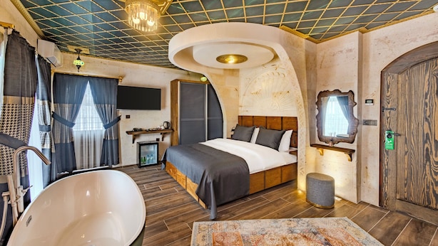 Une chambre moderne dotée d’un grand lit, d’une baignoire et d’un design de plafond original.