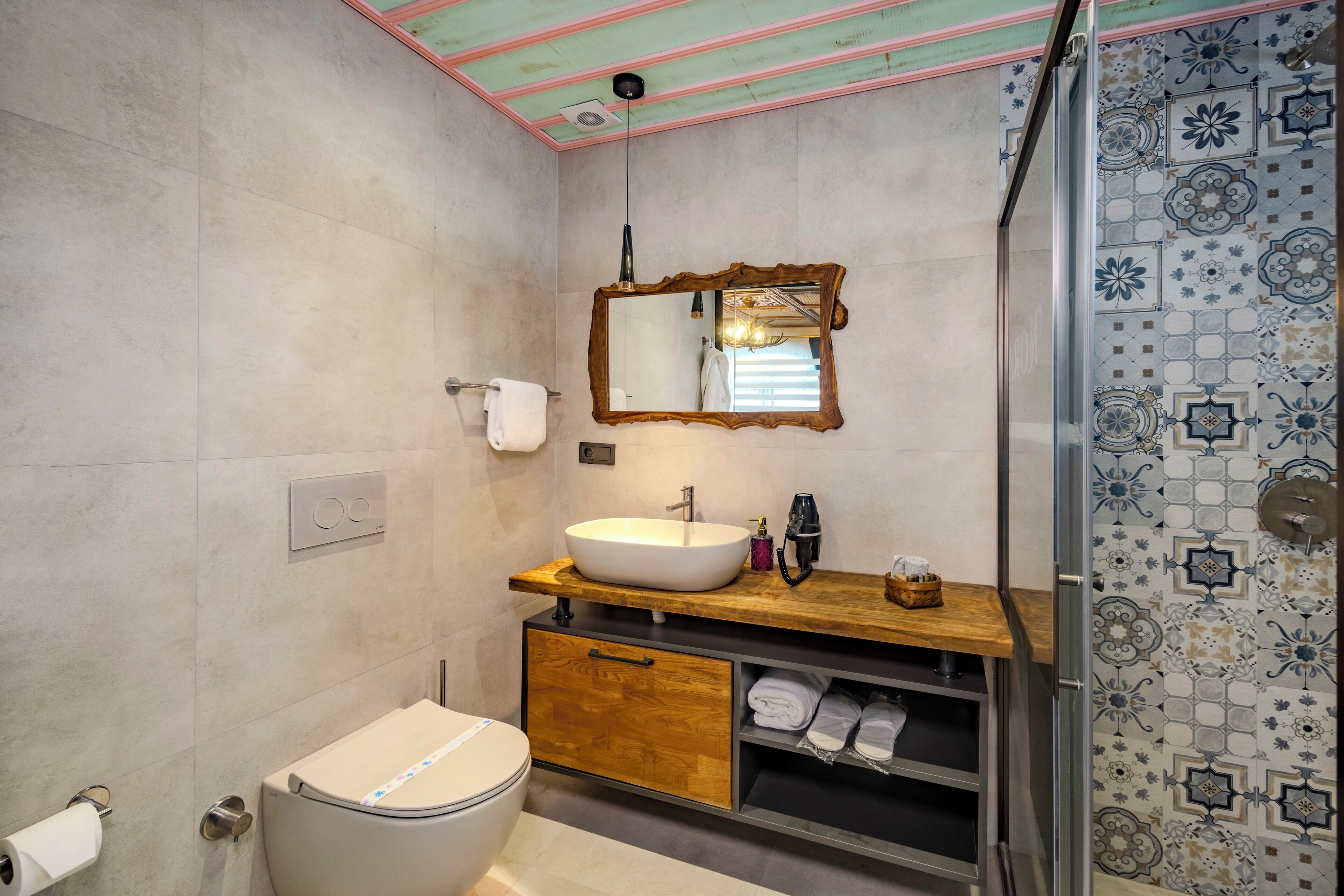 A bathroom with a toilet, sink, mirror, and shower.