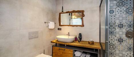 A bathroom with a toilet, sink, mirror, and shower.