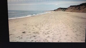 Ein Strand mit sandigem Ufer und einer Klippe im Hintergrund.
