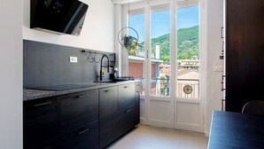 Een moderne keuken met donkere kastjes, een ingebouwde magnetron en uitzicht op een balkon met stadsbeeld en heuvels.
