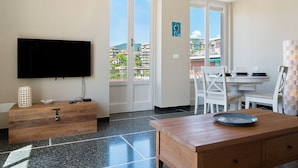 Een kamer met een televisie, een houten bureau, een eettafel en een balkon met uitzicht.