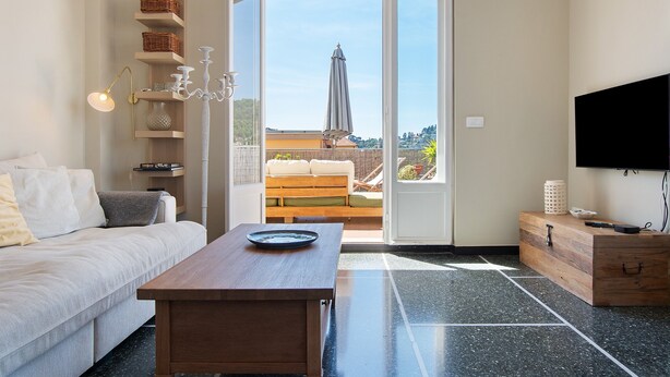Een moderne woonkamer met een bank, een houten salontafel, een televisie en een balkon met uitzicht.