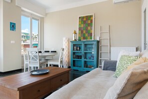 A room with a bed, a desk, a chair, a cabinet, and a window with a view of buildings. - Apartment 'Casa La Perla' with Wi-Fi and Air Conditioning (Rapallo)