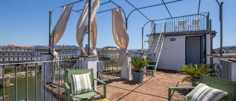 A rooftop terrace with a table, chairs, and a bowl of fruit.