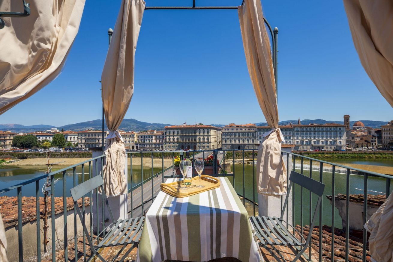 Un tavolo con una tovaglia a righe e un vassoio, con vista su un fiume e edifici sullo sfondo.