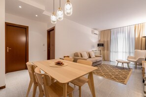 A modern living room with a wooden dining table, beige sofa, and a patterned rug. - Artemisia B2 12 by Wonderful Italy (Sirmione)